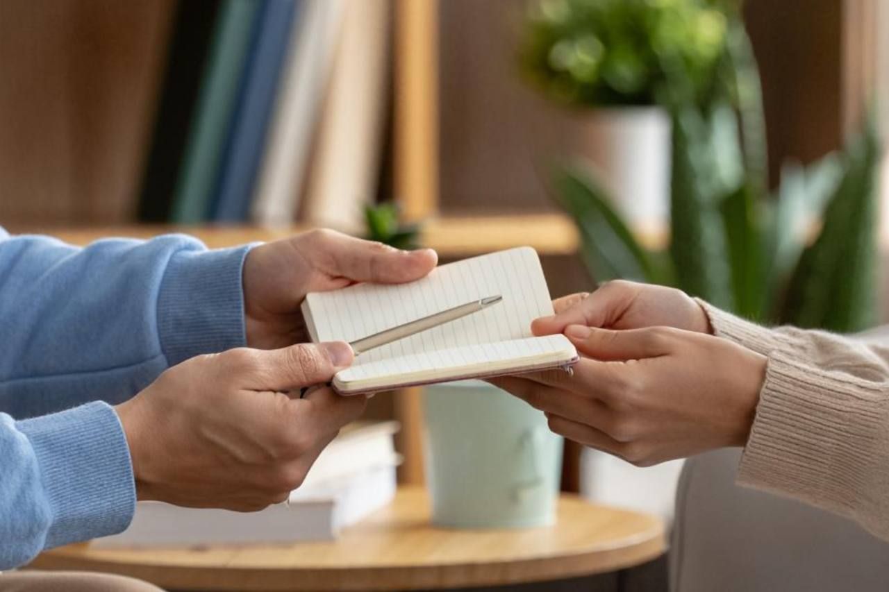 Психортерапевт передает блокнот пациенту